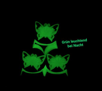 Drei leuchtende grüne Schmetterlinge auf schwarzem Hintergrund, mit dem Text „Grün leuchtend bei Nacht“.
