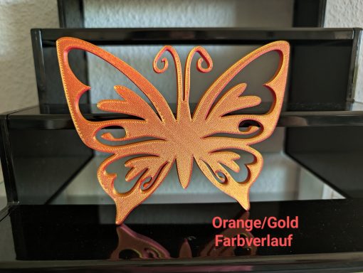 Schmetterling in Orange/Gold auf einer reflektierenden schwarzen Oberfläche.