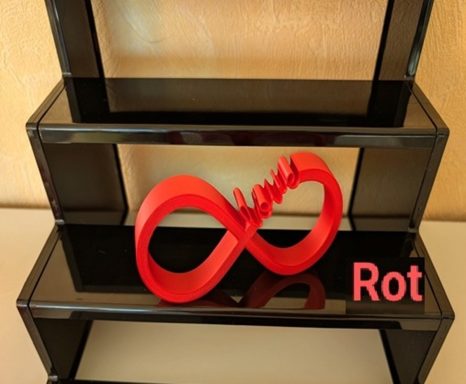 Rote Infinity-Symbolskulptur auf einem Regal in Schwarz.