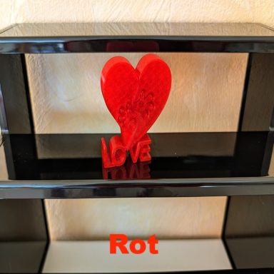 Rotes Herz mit der Aufschrift "Love" auf einem schwarzen Regal.