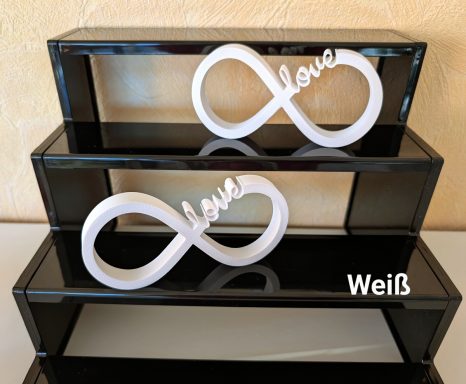 Zwei weiße Unendlichkeitssymbole mit dem Schriftzug "love" auf schwarzen Regalen.