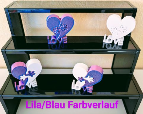 Drei Dekoherzen in Lila-Blau mit dem Schriftzug "LOVE" auf schwarzen Regalen.