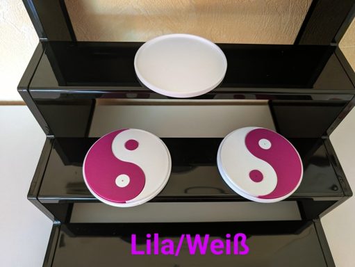Zwei Yin-Yang-Symbole in Lila und Weiß auf einem schwarzen Regal.